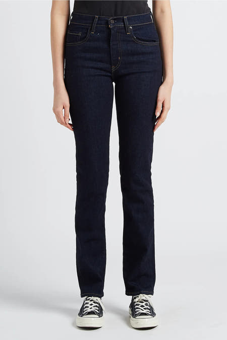 Jean bleu marine droit de Levi's, avec des poches arrière et une étiquette en cuir marron, associé à des baskets noires.