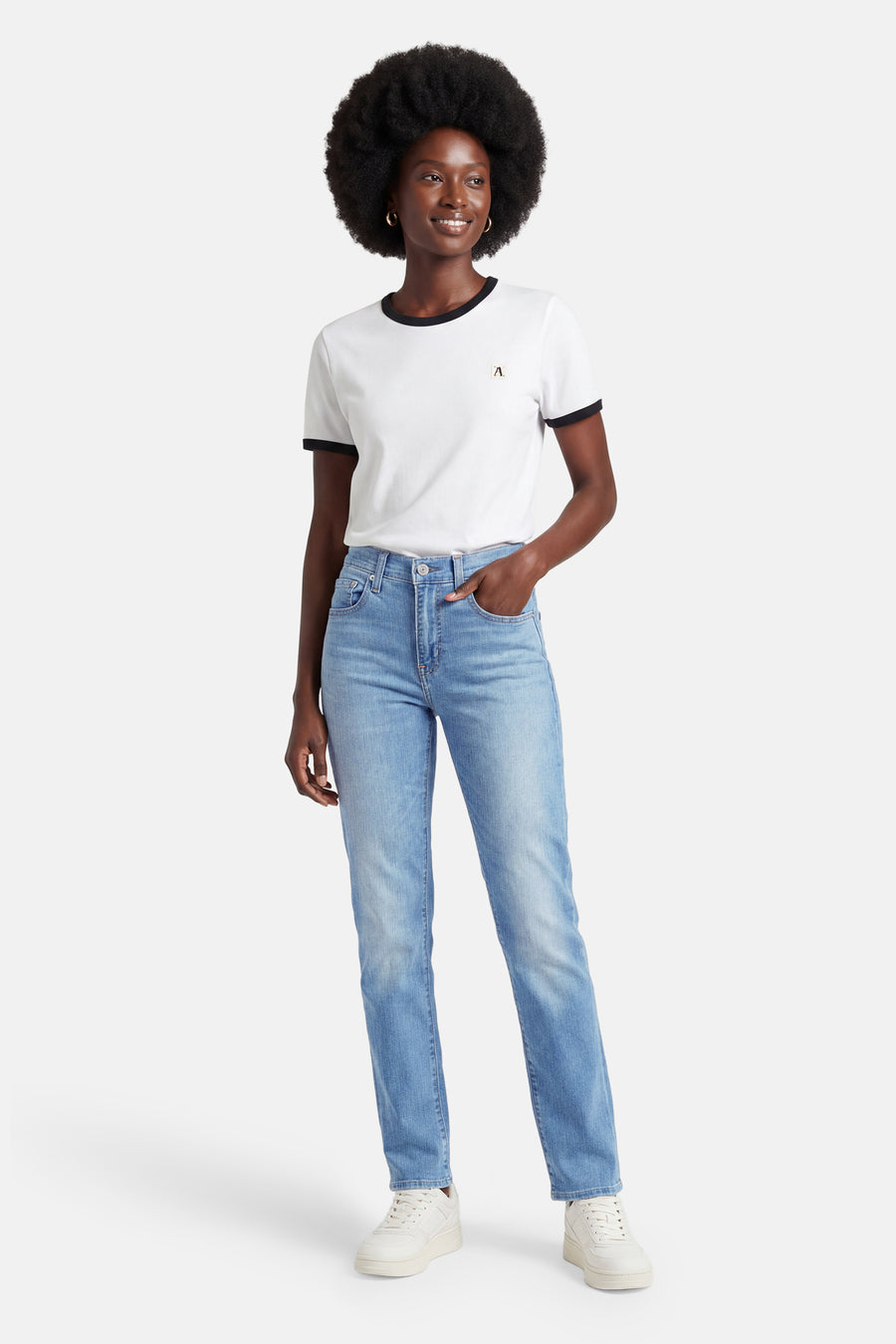 Rechte jeans van lichtblauw denim van Levi's®, gedragen met een wit T-shirt met zwarte biezen en witte sneakers.
