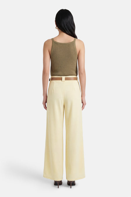 Pantalon jaune de Terra di Siena, à jambes larges et avec une ceinture marron, vu de dos.