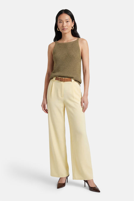 Pantalon jaune de Terra di Siena, avec ceinture marron et jambes larges, combiné avec des escarpins marron et un haut vert.