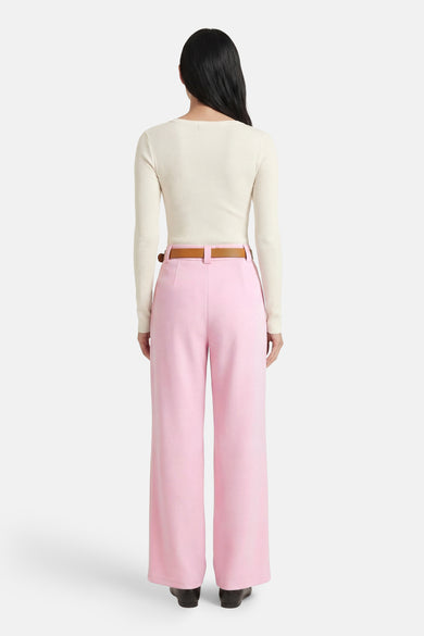 Roze broek van Terra di Siena, met wijde pijpen, gecombineerd met een ecrukleurige top en bruine riem, gezien vanaf de achterkant.
