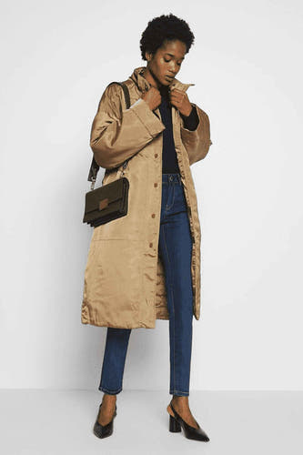 Donkerblauwe skinny jeans van Morgan De Toi, gecombineerd met een lange jas en zwarte hakken.