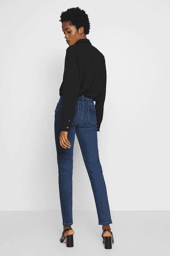 Skinny jeans van donkerblauw denim van Morgan De Toi, gezien van achteren, gecombineerd met een zwarte blouse en hoge hakken.
