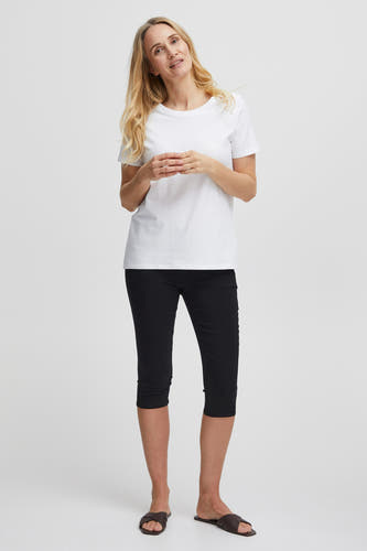 Wit T-shirt met korte mouwen van Fransa, gedragen met zwarte driekwart broek en bruine sandalen.
