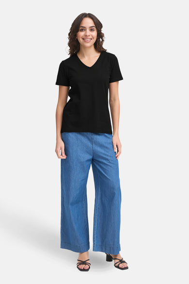 T-shirt noir à manches courtes de Fransa, porté avec des jeans larges et des sandales à talon.