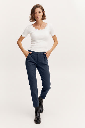 Blauwe chino van Fransa, gecombineerd met een wit kanten shirt en zwarte laarzen.
