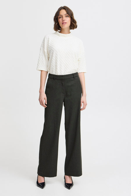 Grijze broek van Fransa, met een wijde pijp en gedragen met een witte top.
