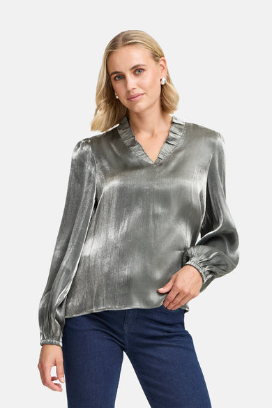 Zilverkleurige blouse met lange mouwen van Fransa, met een V-hals met ruches en gedragen met een donkere jeans.

