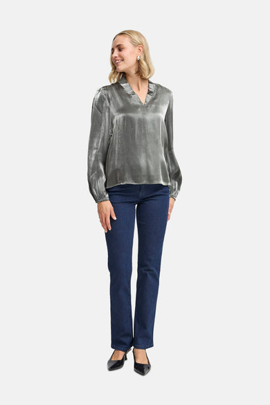 Zilveren blouse met lange mouwen van Fransa, met plooien bij de hals en gedragen met een donkere jeans.
