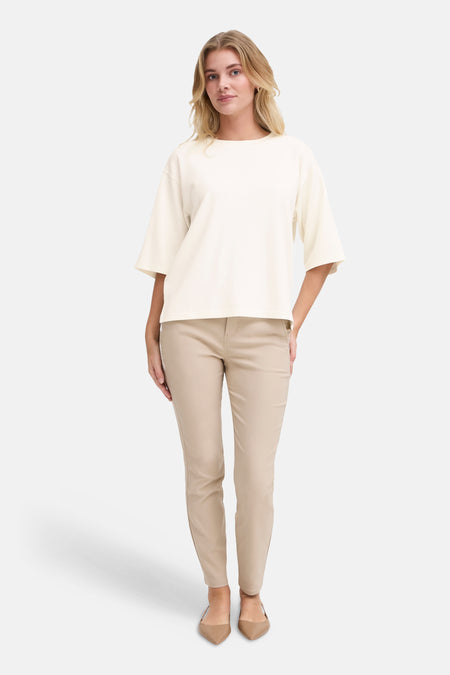 Ecru sweater met ronde hals van Fransa, gecombineerd met een beige broek en spitse schoenen.