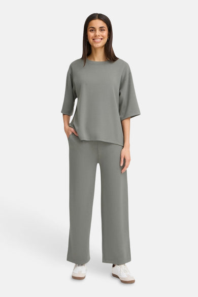 Kaki broek van Fransa, met wijde pijpen en gedragen met een bijpassend shirt.
