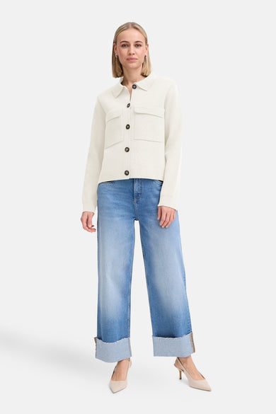 Ecru gilet van Fransa, met bruine knopen en opgestikte zakken, gecombineerd met blauwe jeans en pumps.
