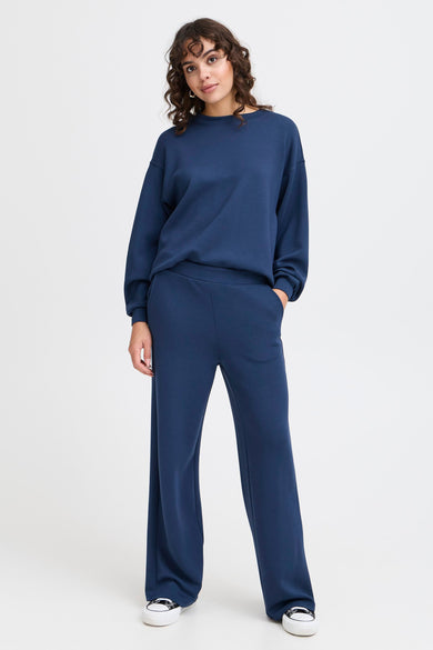 Pantalon de jogging bleu de Fransa, avec des jambes larges et associé à un pull bleu et à des baskets blanches.