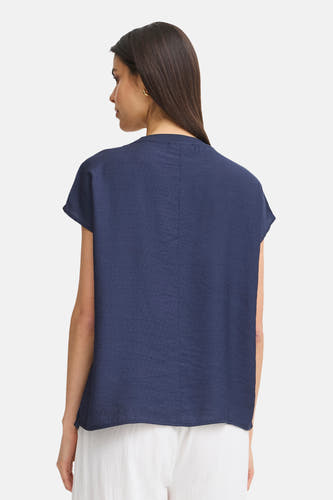 Blauwe blouse met korte mouwen van Fransa, achterkant gezien, met subtiele textuur en gouden oorbel.