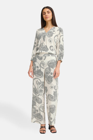 Ecru broek van Fransa met paisleyprint en een bijpassende blouse, gecombineerd met zwarte sandalen.
