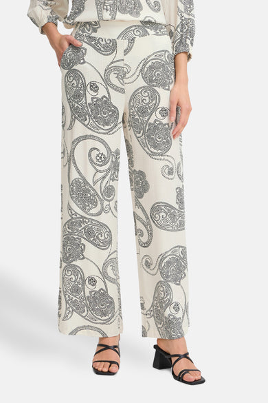 Ecru broek van Fransa, met paisley-print en een vloeiende pasvorm, gecombineerd met zwarte sandalen.
