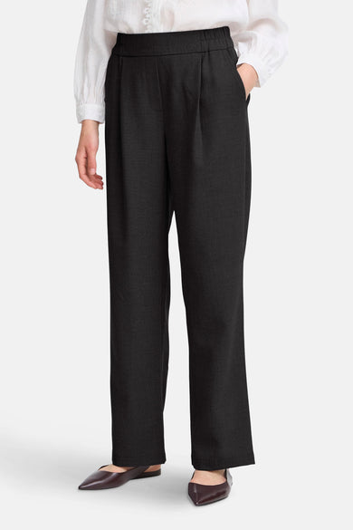 Zwarte broek van Fransa, met plooien aan de voorkant en gecombineerd met een witte blouse en bruine schoenen.
