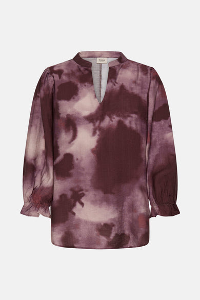 Blouse rouge à longues manches de France, avec imprimé batik flou et une fente au col.