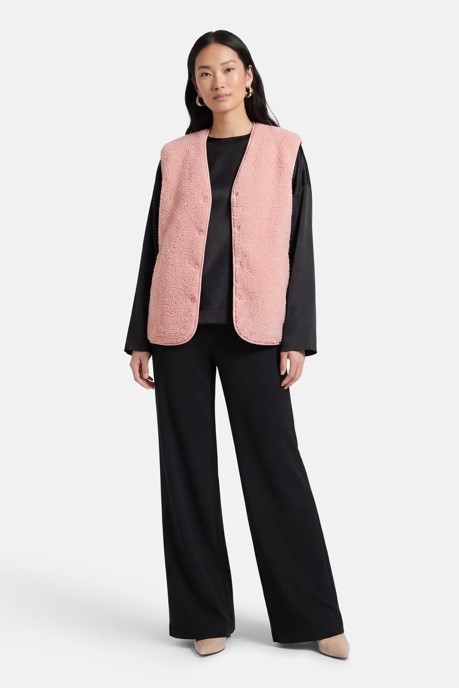Gilet rose de Fransa, porté sur un haut noir et combiné avec un pantalon noir ample.