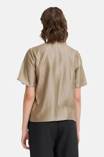 Beige blouse met korte mouwen van Fransa, met subtiele plooien en gedragen met een zwarte broek, gezien van achteren.
