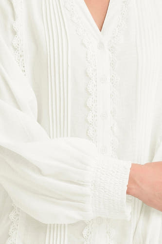 Chemise blanche à manches longues de France, finie avec des plis et des détails en biais, et un col élastique.