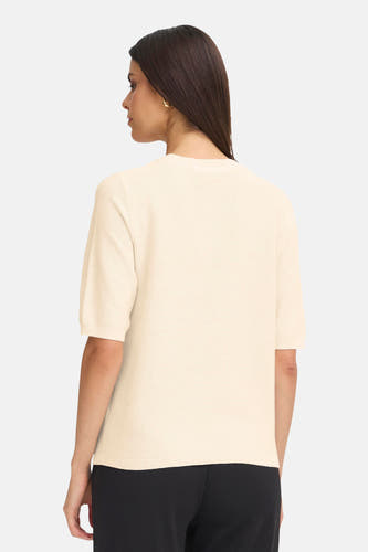 Pull beige avec col rond de France, dos visible, associé à un pantalon noir.