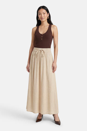 Jupe longue beige de Fransa, avec une taille élastique et des escarpins marron.