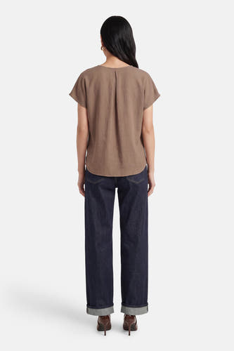 Beige blouse met korte mouwen van Fransa, gezien van achteren, gecombineerd met donkere jeans en hakken.