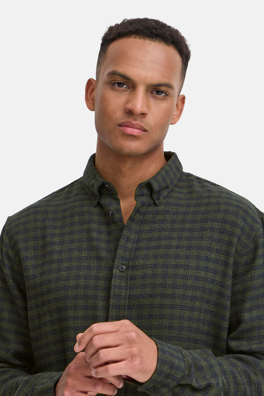 Een man in een olijfgroen geruit overhemd met lange mouwen.