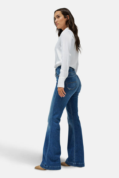 Jean en denim bleu évasé de Salsa Jeans, associé à un t-shirt blanc, en vue latérale.
