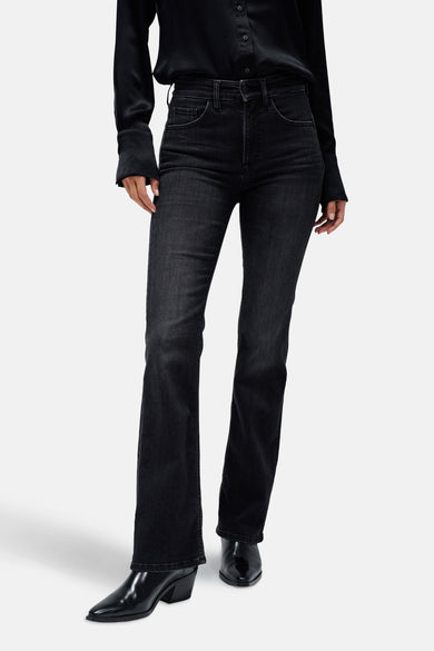Jeans bootcut van donkergrijs denim van Salsa Jeans, met een subtiele uitlopende pijp en zwarte leren laarzen.
