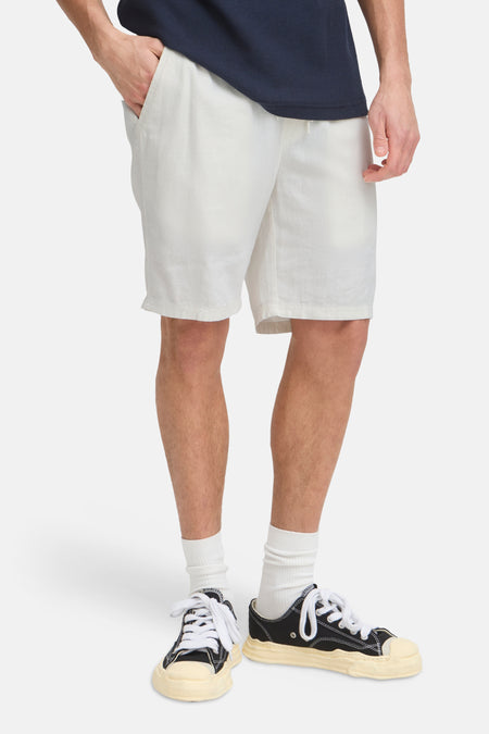 Witte shorts van SOLID met trekkoord, gedragen door een man met een marineblauw shirt en zwarte sneakers.