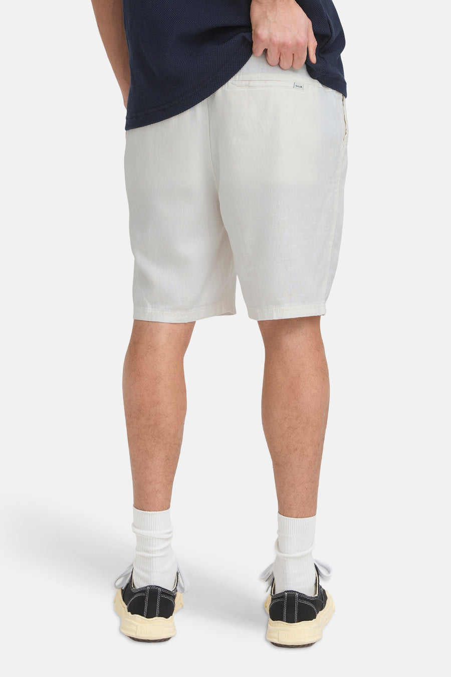 Short de couleur crème de SOLID, vue arrière, avec une texture subtile et une petite étiquette sur la poche arrière, porté avec un t-shirt bleu foncé et des baskets.