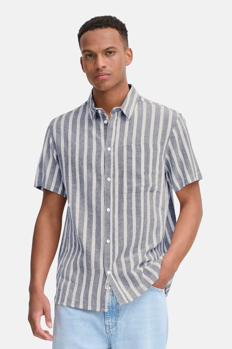 Chemise rayée bleue de SOLID, à manches courtes et portée avec un jean bleu clair et des baskets blanches.