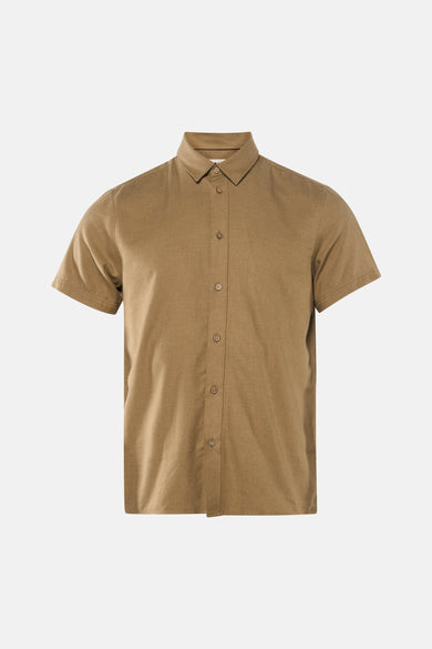 Chemise kaki à manches courtes de SOLID, portée avec un jean bleu et des baskets beiges.