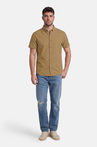Kaki hemd met korte mouwen van SOLID, gedragen met blauwe jeans en beige sneakers.