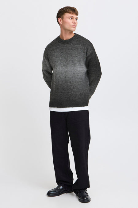 Grijze trui met ronde hals van SOLID, met een subtiel kleurverloop en gecombineerd met een wit T-shirt en zwarte broek.
