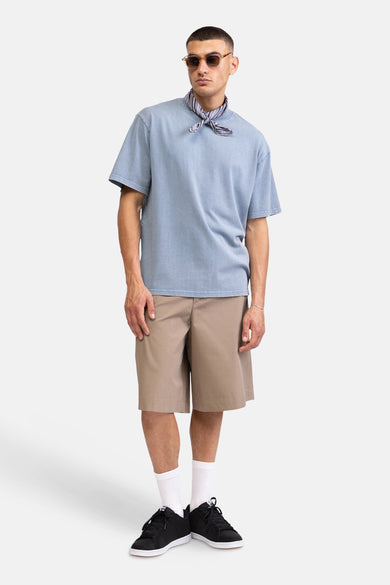 T-shirt bleu à manches courtes de REDEFINED REBEL, porté avec une écharpe rayée, un short kaki et des baskets noires.