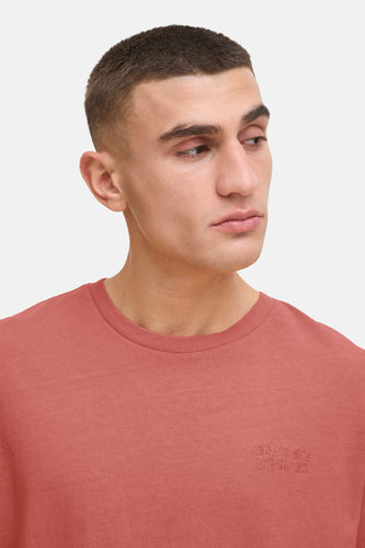 Man in perzikkleurig T-shirt met korte coupe.