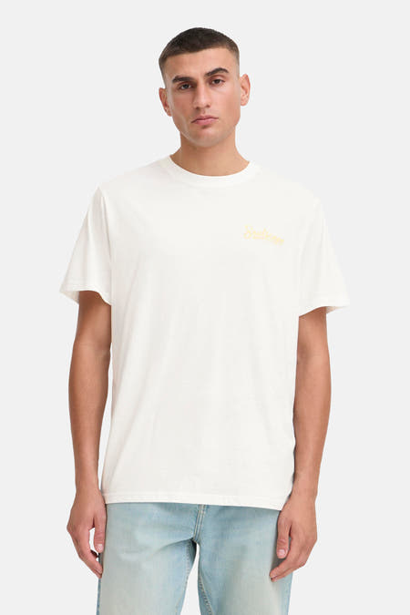 T-shirt blanc à manches courtes de SOLID avec une impression jaune. L'ensemble est complété par un jean bleu clair et des baskets.