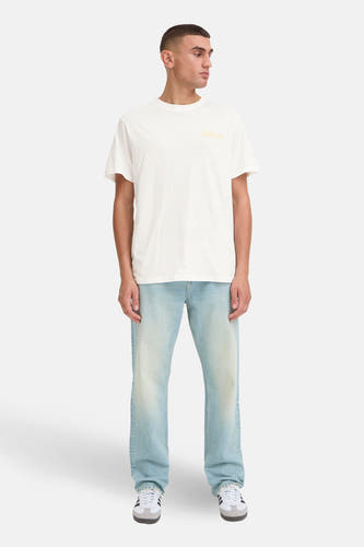 Wit T-shirt met korte mouwen van SOLID, met een gele opdruk. De outfit wordt gecompleteerd door een lichtblauwe jeans en sportschoenen.