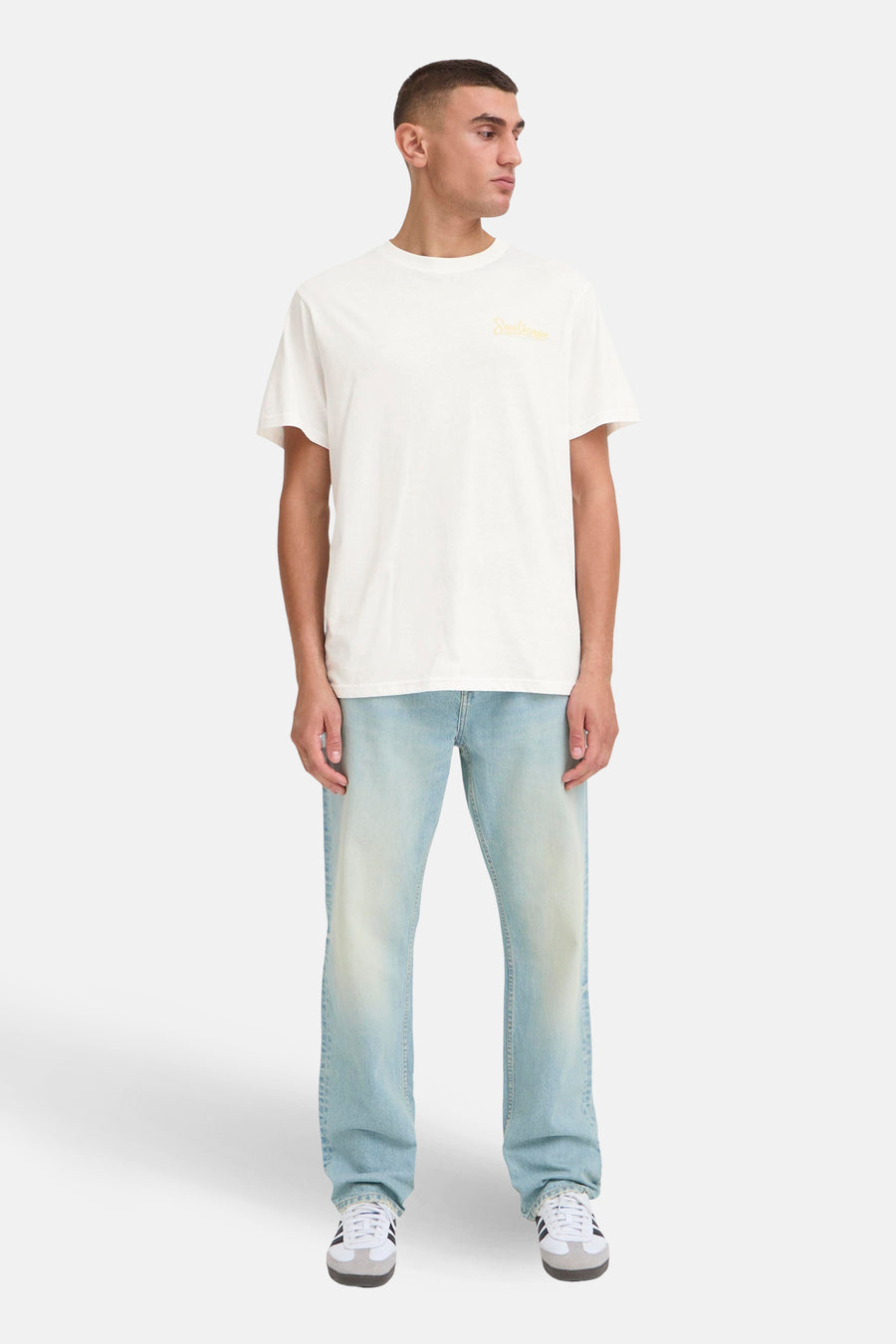 Wit T-shirt met korte mouwen van SOLID, met een gele opdruk. De outfit wordt gecompleteerd door een lichtblauwe jeans en sportschoenen.