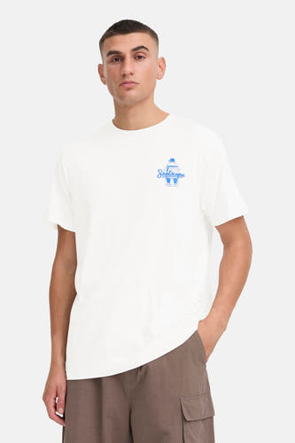 T-shirt blanc à manches courtes de SOLID, avec imprimé bleu, porté avec un pantalon cargo marron et des baskets blanches.