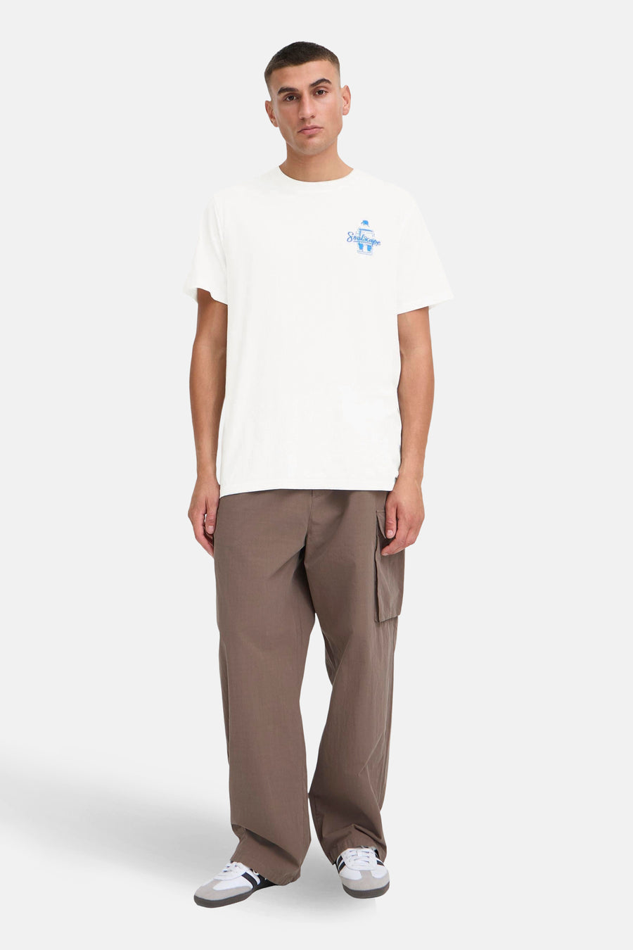 Wit T-shirt met korte mouwen van SOLID, met blauwe print, gedragen met bruine cargobroek en witte sneakers.
