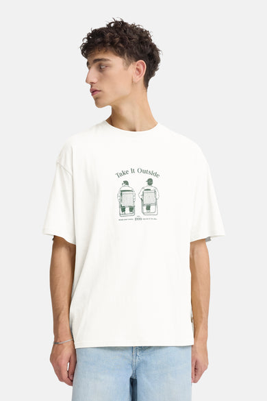 T-shirt blanc à manches courtes de SOLID, avec imprimé vert sur la poitrine, combiné avec un short en jean et des baskets blanches.