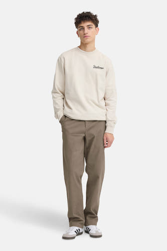 Bruine chino van SOLID, gedragen met een beige sweatshirt en witte sneakers met zwarte strepen.
