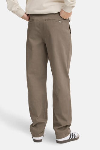 Bruine chino van SOLID, gezien vanaf de achterkant, met beige sweater en Adidas Samba sneakers.