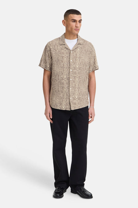 Bruin hemd met korte mouwen van SOLID, met licht krullend patroon en reverskraag, gecombineerd met zwarte broek en loafers.