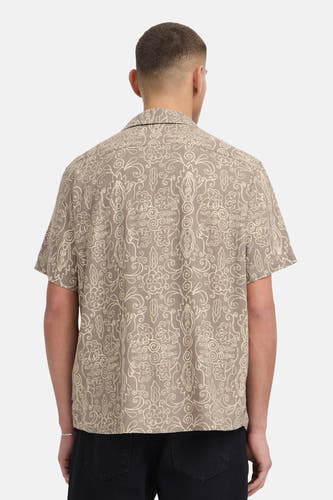 Bruin hemd met korte mouwen van SOLID, met off-white decoratief patroon, gedragen door een man van achteren gezien met zwarte broek en zilveren armband.