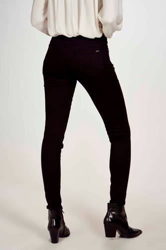 Pantalon noir de Morgan De Toi, vu de l'arrière avec un motif uni et porté avec une blouse blanche et des bottines noires.